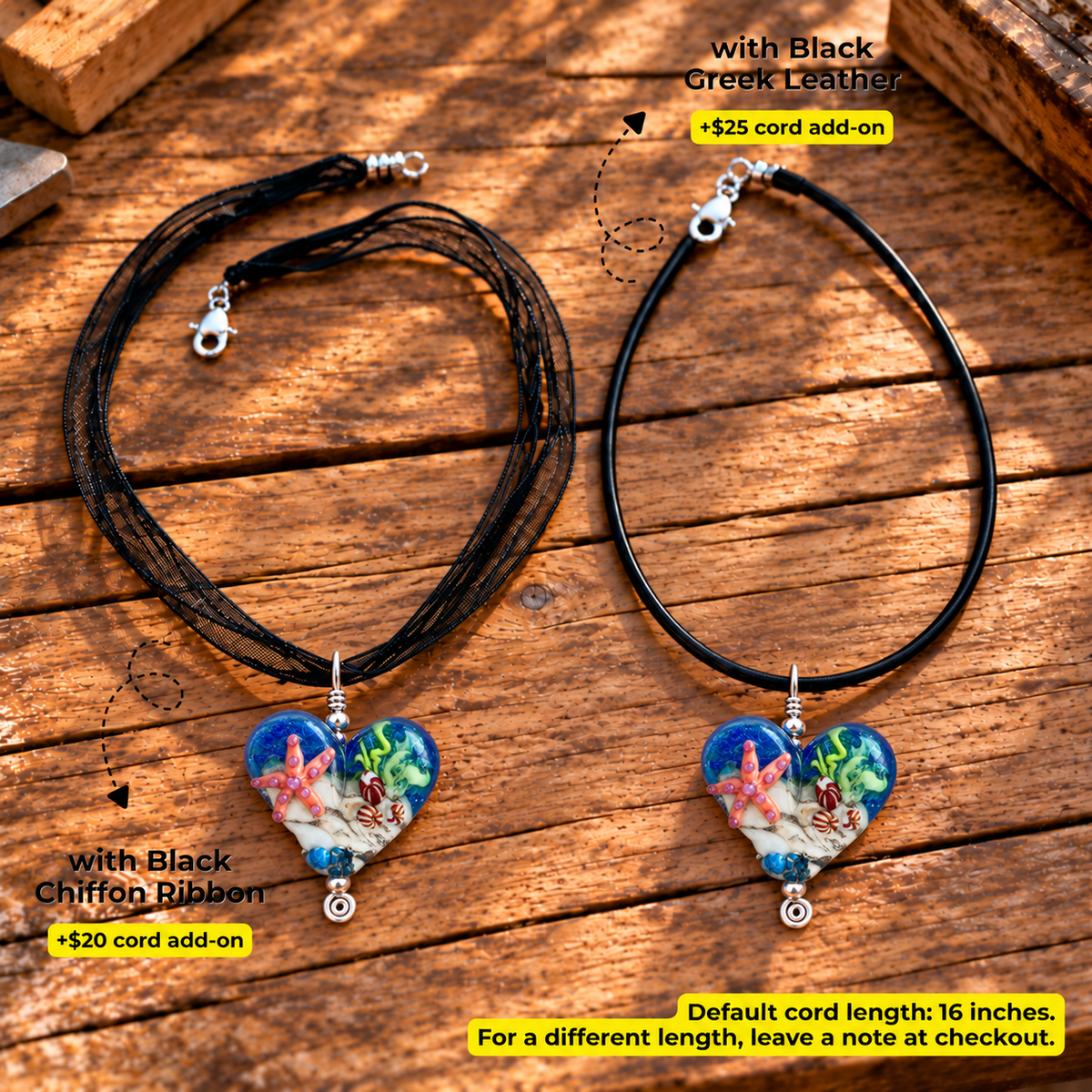 Two heart-shaped glass pendant necklaces displayed on a rustic wooden surface, one with black cord and black chiffon ribbon, and one with black leather. Both feature colorful underwater-themed heart pendants with blue, red, and green details.