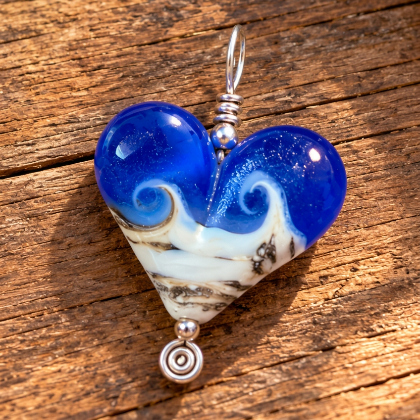 Three heart-shaped glass pendants with a blue and white wave design, displayed on a rustic wooden surface.
