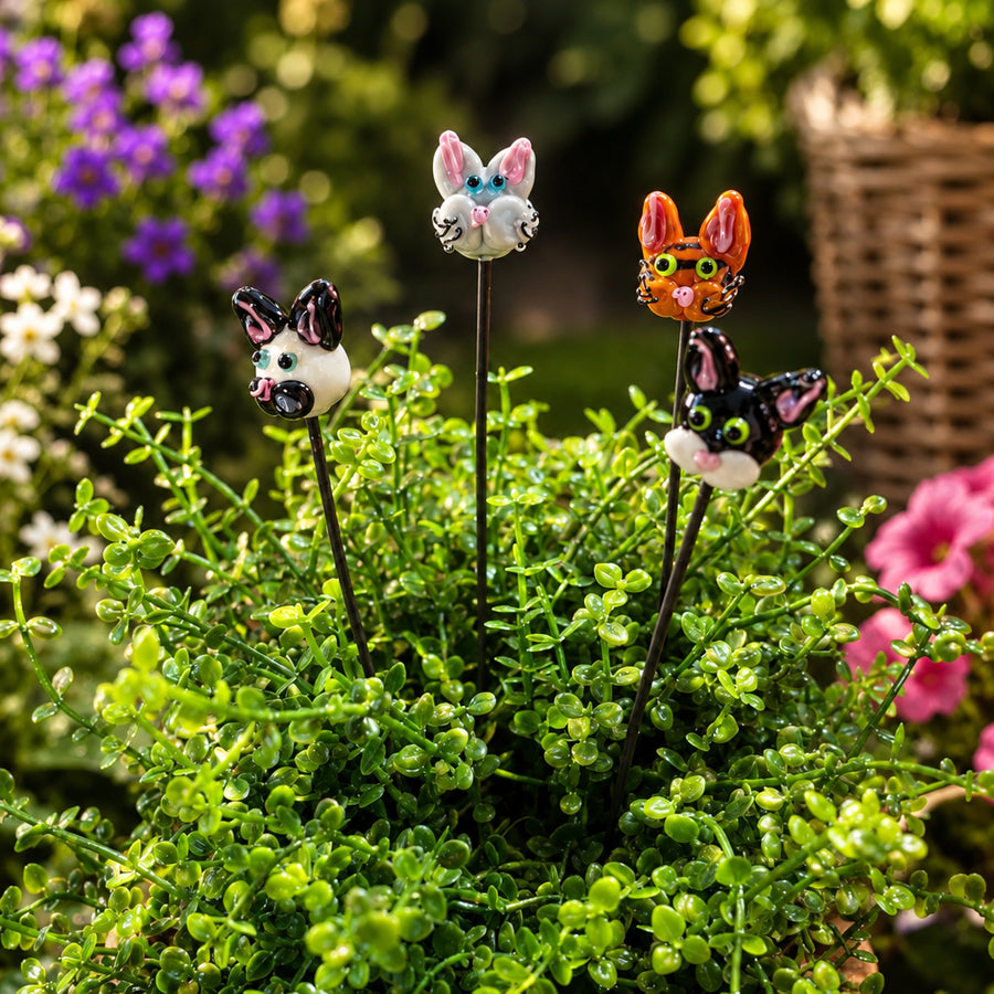 Three decorative plant stake garden markers shaped like a gray bunny, a black-and-white cat, and an orange cat, displayed in a green garden among leafy plants. The 'Plant Sticks Cat Bundle' logo is visible in the top left corner.