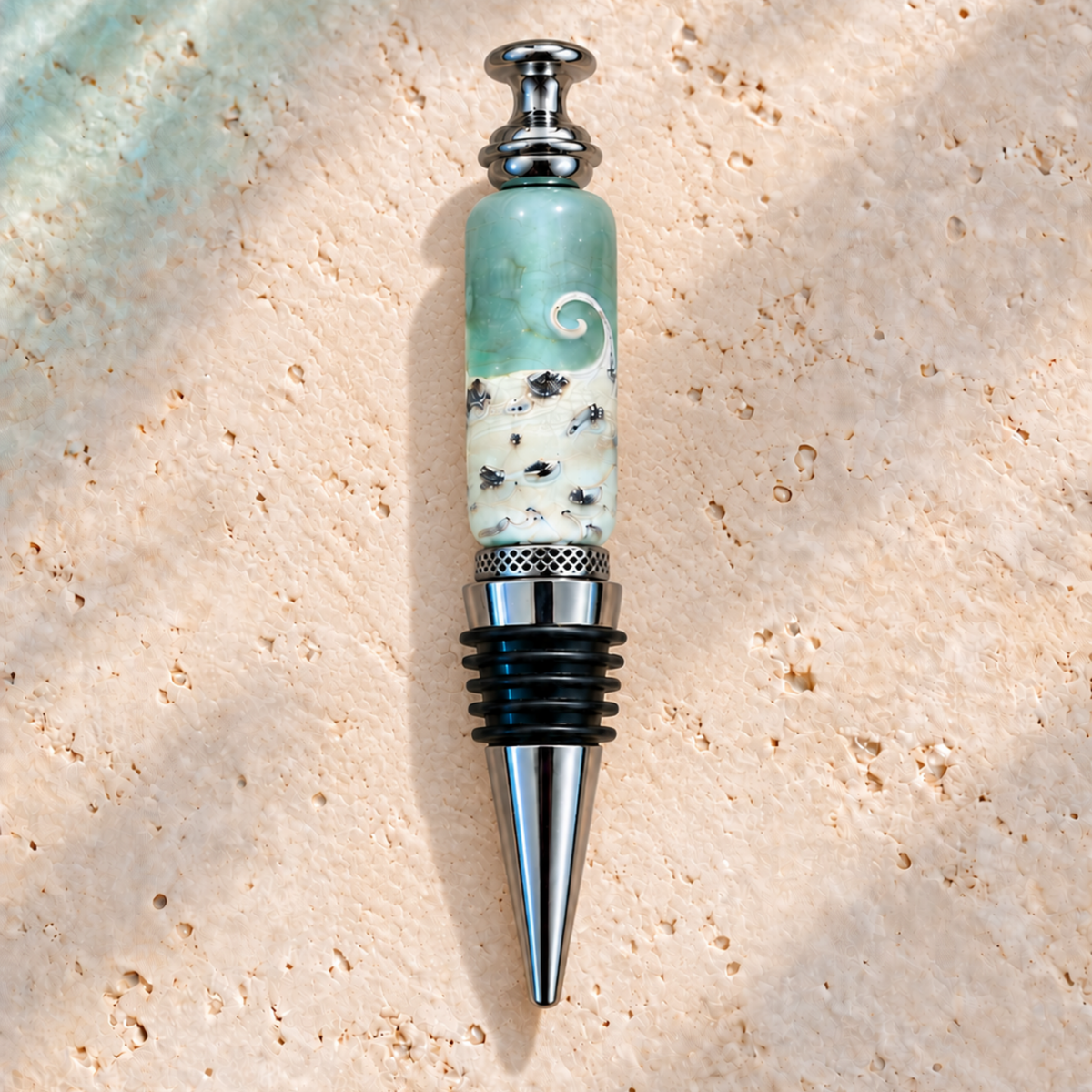 A personalized bottle stopper featuring a light green and white marbled stone body with a white swirl design, resting on a textured beige stone surface.